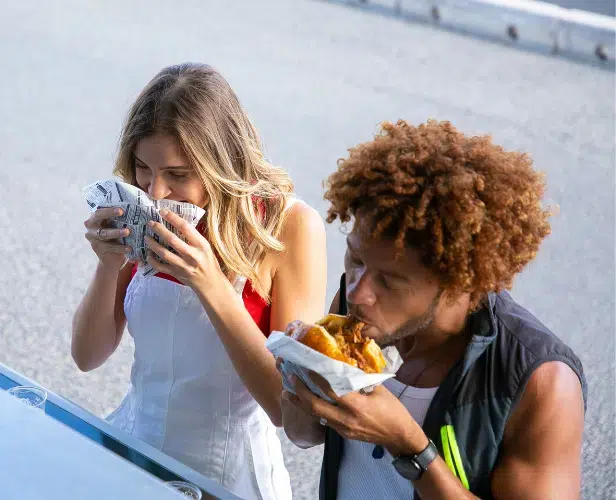 Två personer njuter av street food vid en food truck.